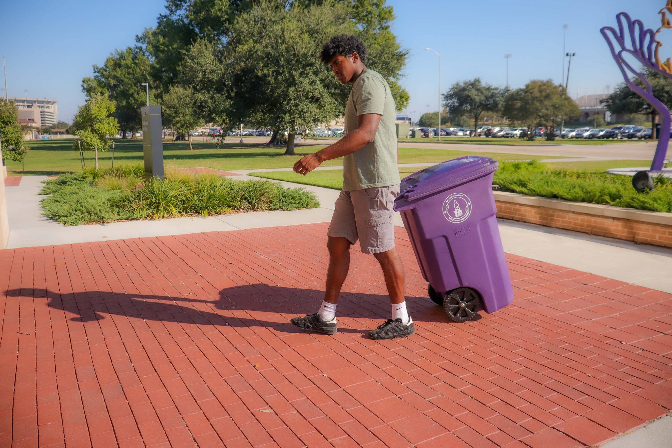 student carrying glass recycling bin