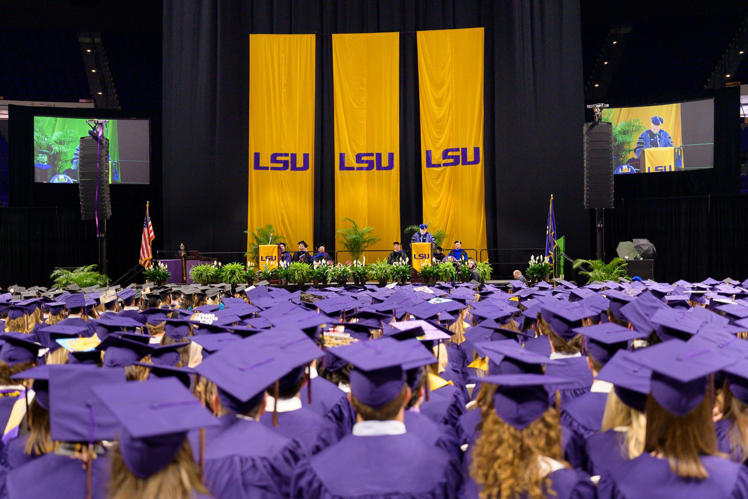 Crowd of graduates in purple caps and gowns at commencement ceremony. 