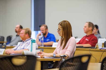 students in lecture hall listen and take notes in class. 