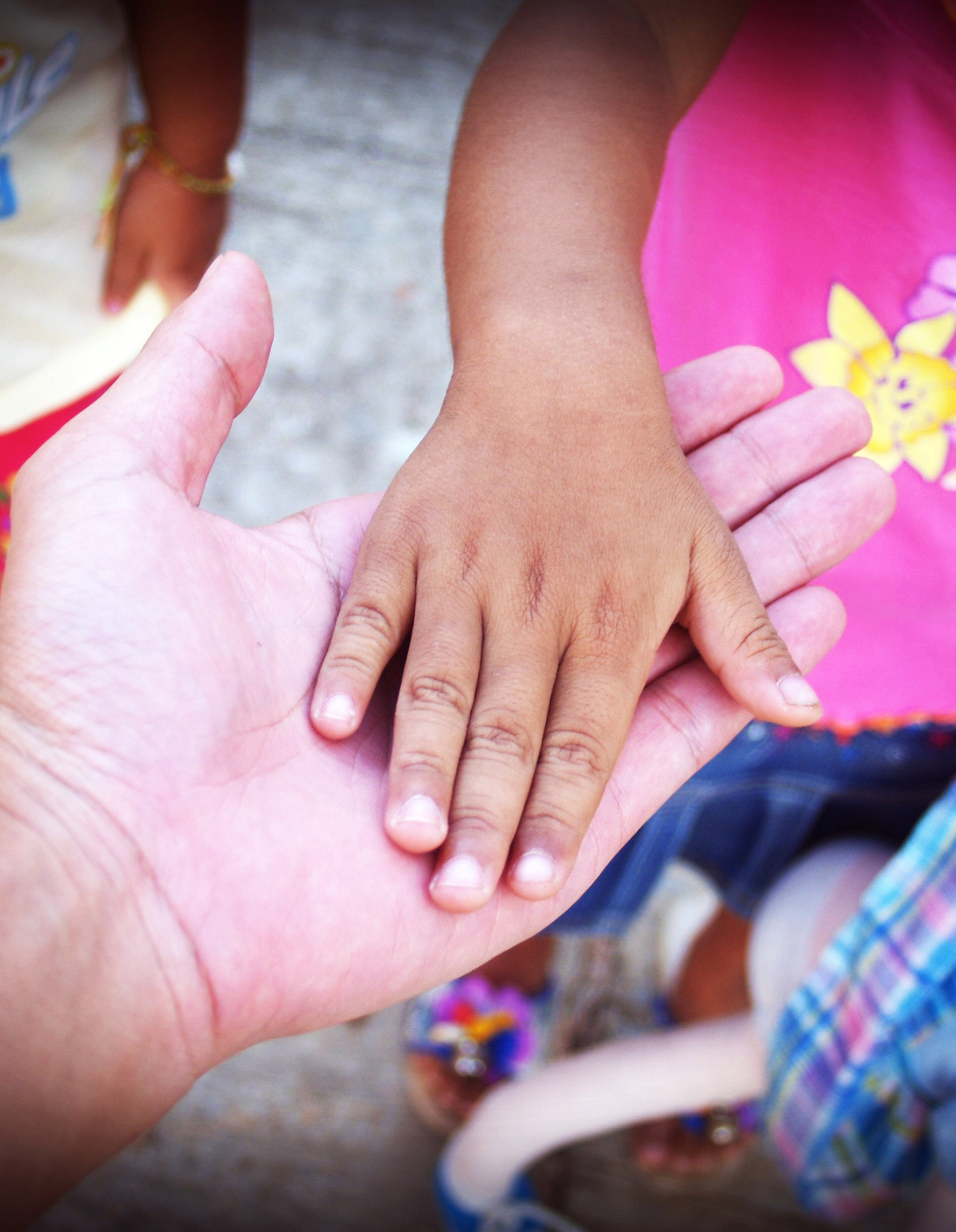 An adult hand holding a childs hand